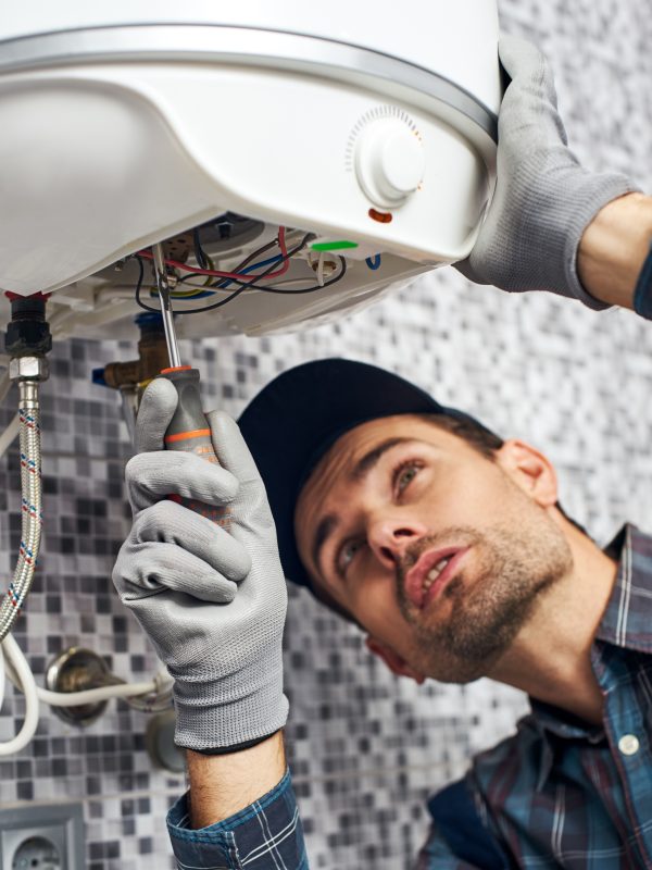 Set up boiler. Worker set up electric heating boiler at home. Close-up of young handyman