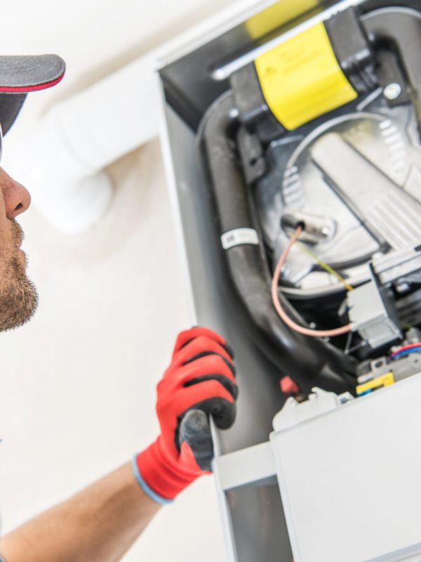 Technician and the Heater Issue. Caucasian Worker Looking Inside Central Gas Heater Trying to Fix the Problem.