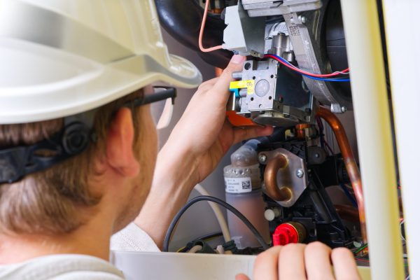 Maintenance and Repair of a gas boiler, setting up and servicing. Technician servicing the gas boiler for hot water and heating. heating servicing concept